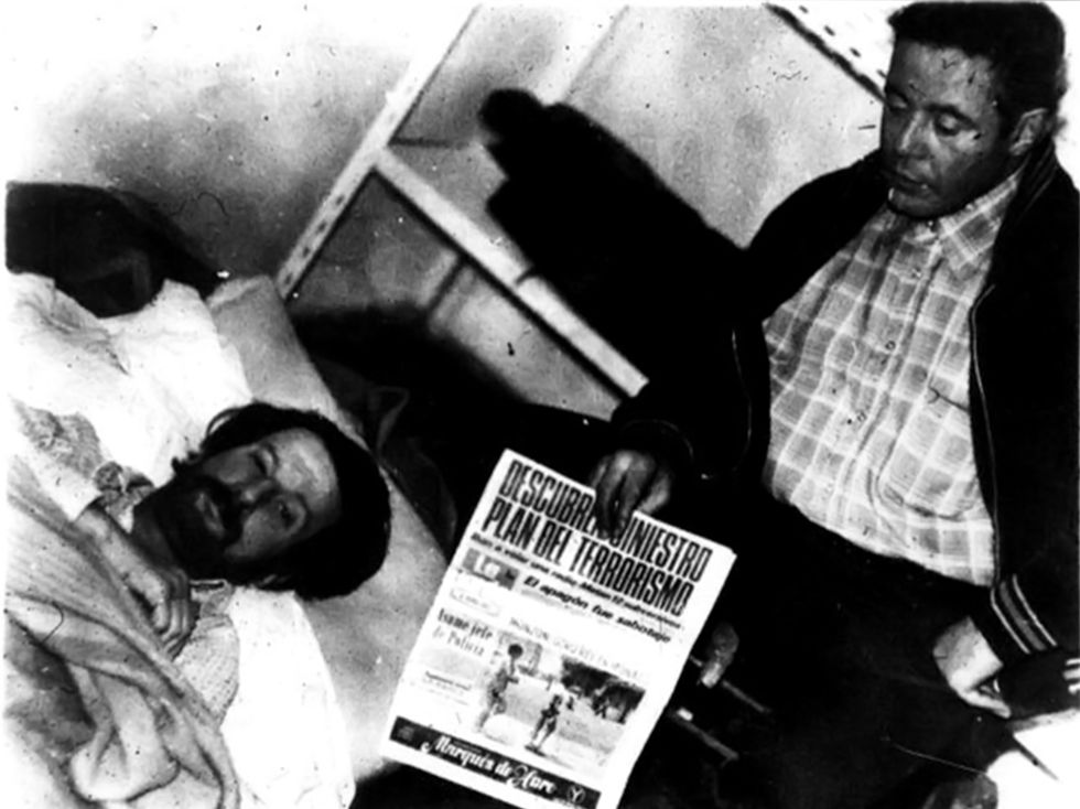 Fotografía de Gerardo Gatti junto a Washington Pérez tomadas por sus captores en el Centro Clandestino de Automotores Orletti. Se muestra un diario de la fecha como parte de una extorsión a sus compañeros por parte de represores argentinos y uruguayos.